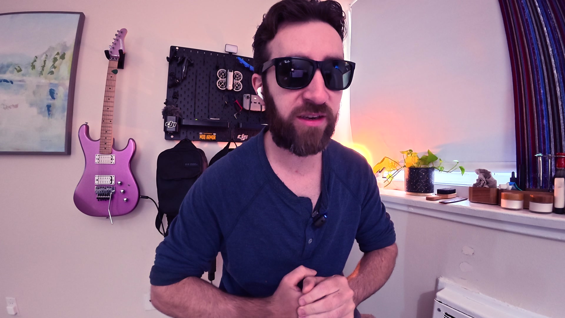 Joshua Ferris in sunglasses, with a purple electric guitar on the wall behind him